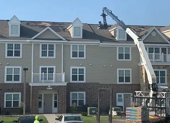 Shingles being placed on the roof by a crane at apartment building.