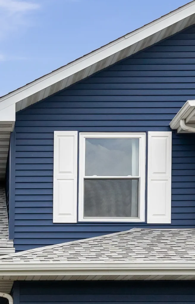 Blue house with white trim and windows against a clear sky.