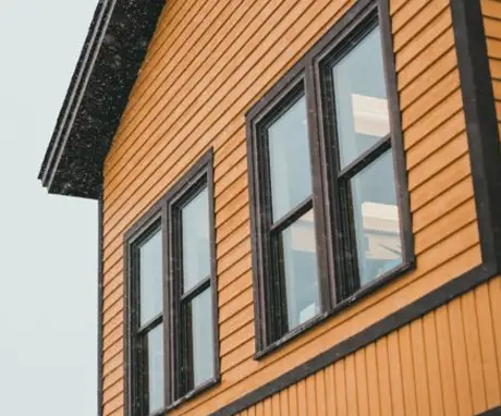 Detailed view of a house with windows and orange siding, capturing the essence of home and warmth.
