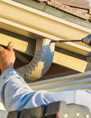 A man installing a gutter using a drill.