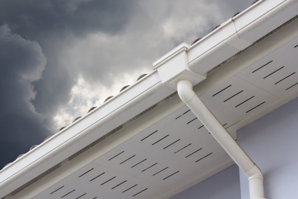 white seamless gutters against a cloudy sky